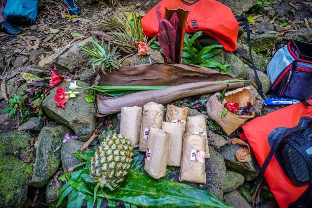 Traditional Hawaiian picnic setup with fresh fruit, wraps, and flowers during a guided Kayak Adventures Kauai tour along the Wailua River.