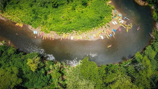 Aerial view of colorful kayaks lined along the Wailua River shore during a Kayak Adventures Kauai tour to Secret Falls.