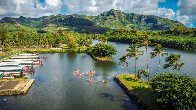 Kayakers launching from the Wailua River docks surrounded by tropical mountains during a Kayak Adventures Kauai guided tour.