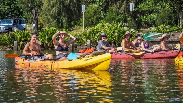 Group of kayakers relaxing on the Wailua River in Kauai, enjoying a break during their Kayak Adventures Kauai guided tour.