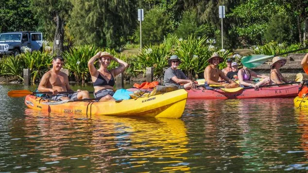 Group of kayakers relaxing on the Wailua River in Kauai, enjoying a break during their Kayak Adventures Kauai guided tour.