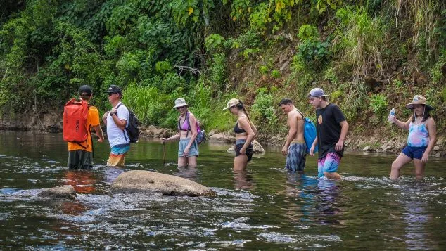 Kayak Adventures Kauai guests crossing a shallow stream on foot during the guided hike to Secret Falls along the Wailua River.